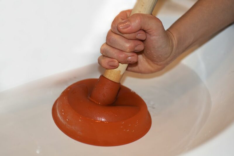 A plunger being used. 6 Common Plumbing Mistakes to Avoid.